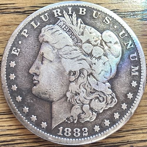 1882S Morgan silver dollar in VERY GOOD condition slightly bent see photo